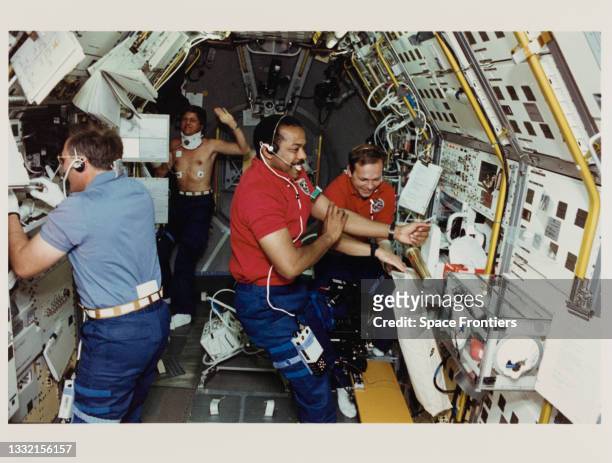American NASA astronaut Jerry L Ross examines a sample tube, German DFVLR astronaut Ulrich Walter wearing a neck brace, American NASA astronaut...