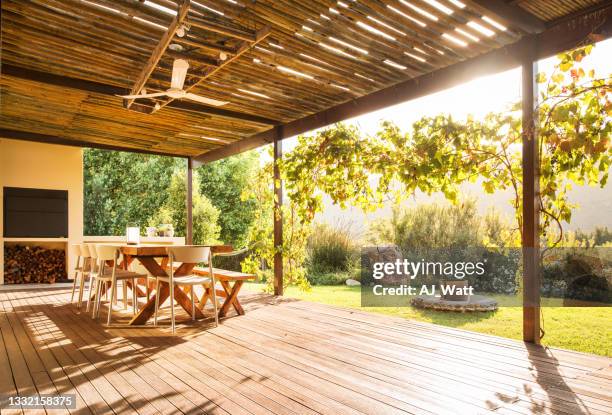 table and chairs on a rustic patio on a sunny afternoon - terrace stockfoto's en -beelden