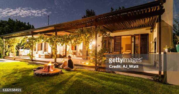 friends talking over drinks next to a campfire in the evening - garden terrace stock pictures, royalty-free photos & images