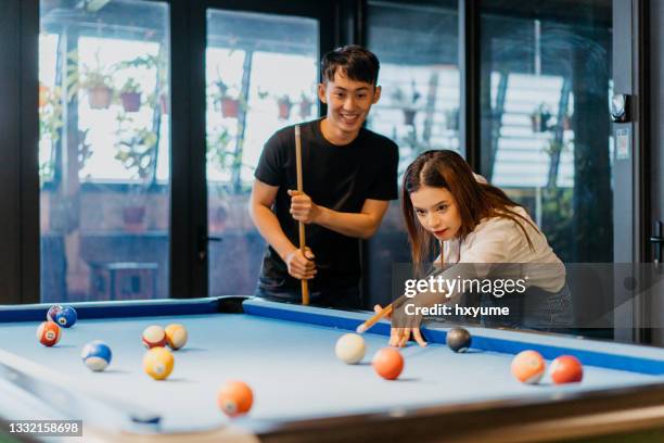 mujer joven jugando al billar con su colega en la sala de juegos de la oficina - pool table fotografías e imágenes de stock