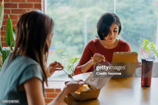 asian businesswoman eating take away lunch in office - employee wellbeing stock pictures, royalty-free photos & images