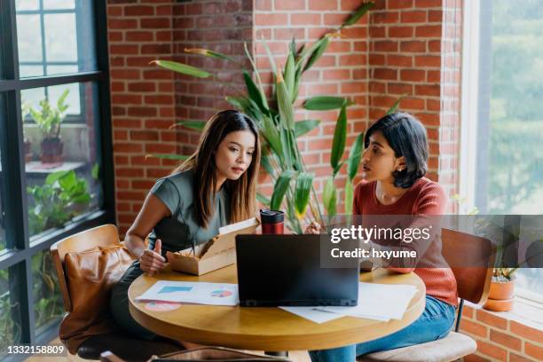 asiatische geschäftsfrauen, die laptopnisch nutzen und in der mittagspause in der lounge diskutieren - indian lunch stock-fotos und bilder