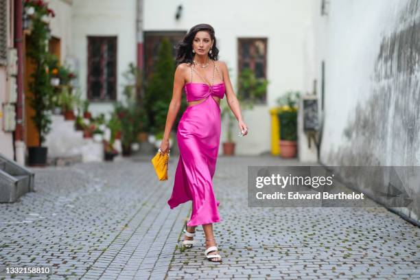 Ioana Visanescu wears a pink / fuchsia shiny satin cut-out / V-neck / split flowing dress with gold chain tank-top shoulders, gold large pearl...