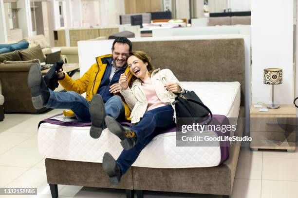 couple having fun buying a bed - matras stockfoto's en -beelden