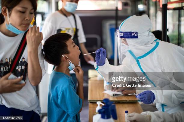 Medical worker takes samples during a mass COVID-19 test in a residential block on August 3, 2021 in Wuhan, Hubei Province, China. Local media has...