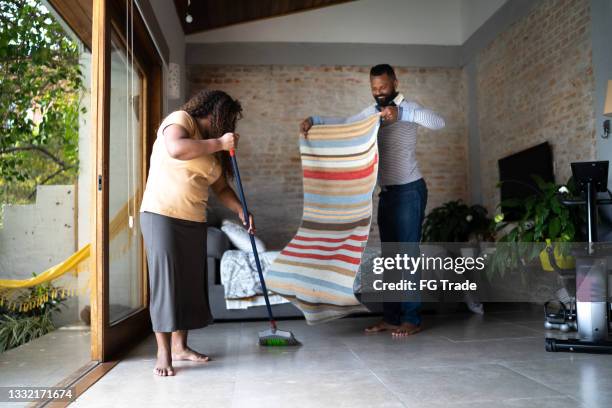 mature couple cleaning house together - sweeping dirt stock pictures, royalty-free photos & images