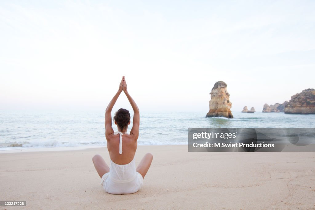 Healthy female meditating along coastlin