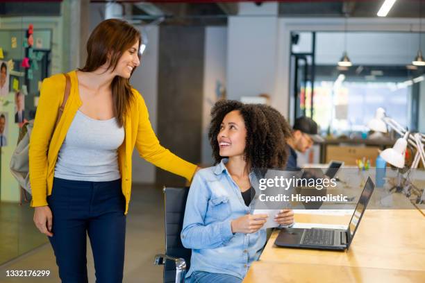 business woman arriving to the office and greeting a coworker at her desk - employee leaving stock pictures, royalty-free photos & images