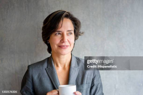 retrato de una mujer latinoamericana reflexiva bebiendo una taza de café - mature latin women fotografías e imágenes de stock