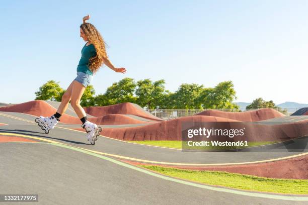 young woman with brown hair enjoying inline skating at pump track on sunny day - inline skate 個照片及圖片檔