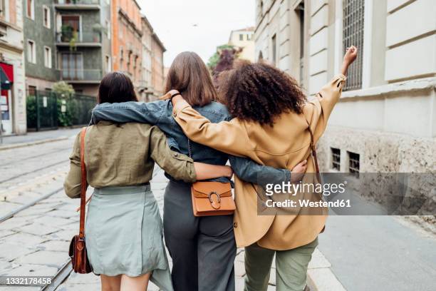 friends walking with arm around at city street - human limb stock pictures, royalty-free photos & images