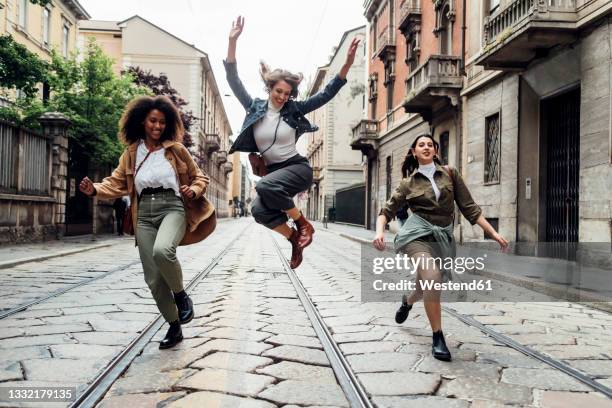 happy friends running together on tramway in city - jump joy stock pictures, royalty-free photos & images