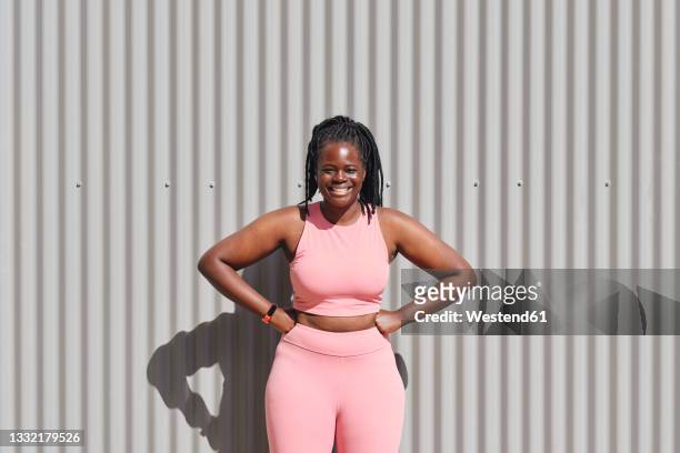 happy curvy young woman with hands on hips in front of corrugated wall - voluptuous black women stock pictures, royalty-free photos & images