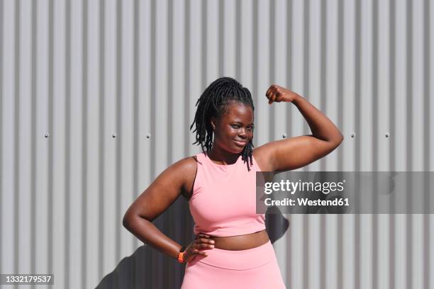 young woman flexing biceps on sunny day - body positive stockfoto's en -beelden