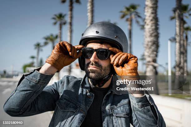 handsome man in helmet wearing sunglasses on sunny day - guanto di pelle foto e immagini stock