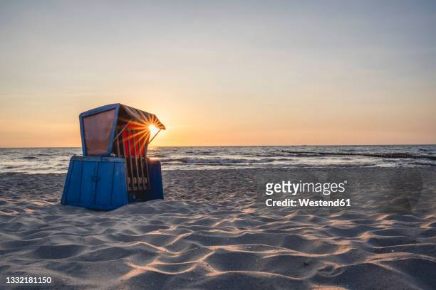 hooded beach chair standing on sandy coastal beach at sunset - usedom photos et images de collection