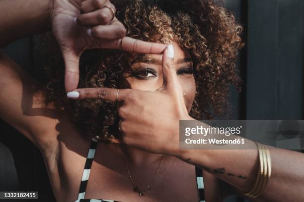 woman looking through finger frame - finger frame stock-fotos und bilder