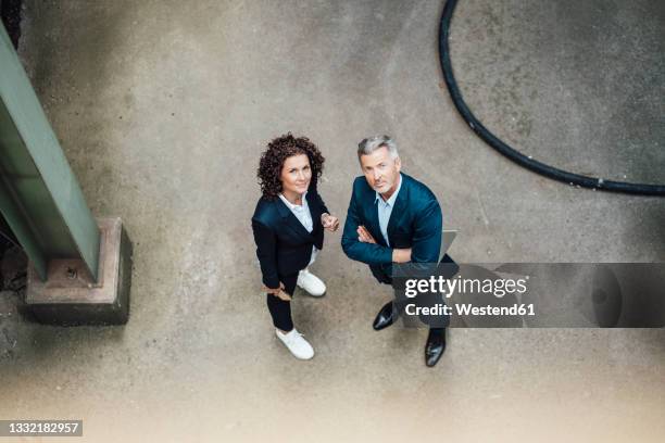 confident businessman standing by colleague on floor in industry - two women stock-fotos und bilder