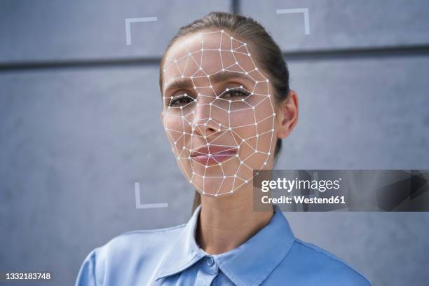 businesswoman with facial recognition biometrics in front of wall - facial recognition technology stock-fotos und bilder