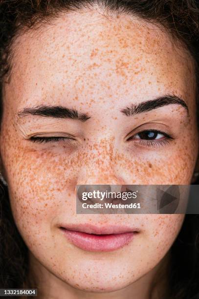 beautiful young woman with freckles winking eye - zwinkern stock-fotos und bilder
