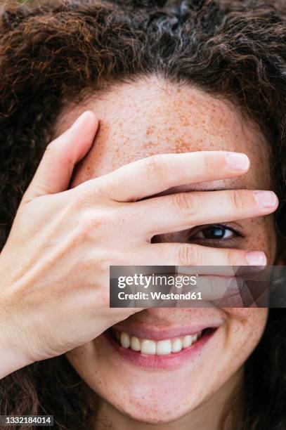 smiling young woman covering eye with hand - peer bildbanksfoton och bilder