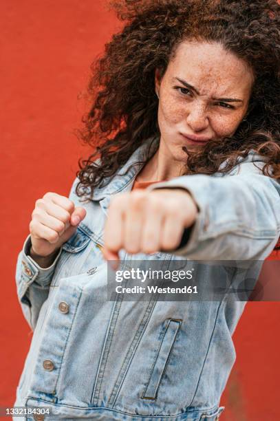 young woman punching with fist while making face - faustschlag stock-fotos und bilder
