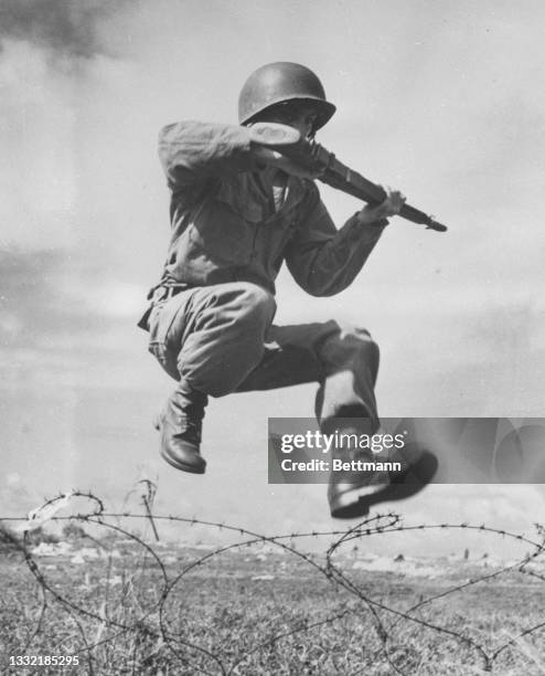 Private Martin Laboy-Santiago, rifle ready, hurdles a mass of barbed wire during an important phase of combat training at Camp Tortuguero.