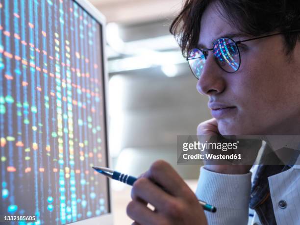 male teenage expert analyzing dna through computer at laboratory - healthcare innovation stock pictures, royalty-free photos & images