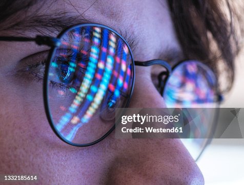 Male teenage scientist with DNA test results reflection on eyeglasses Male teenage scientist with DNA test results reflection on eyeglasses