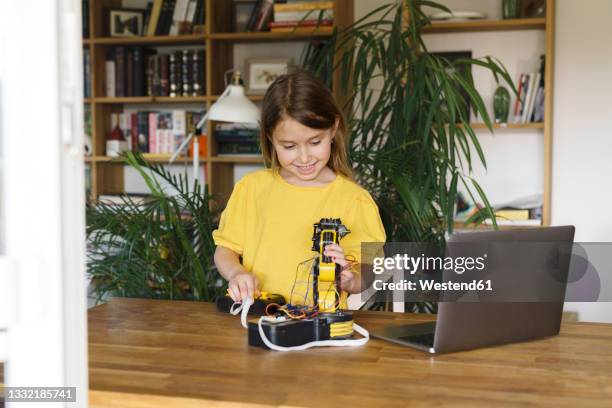 smiling girl operating robotic arm at home - child with robot stockfoto's en -beelden