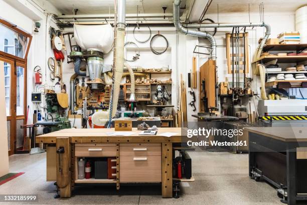 wooden workbench in illuminated workshop - trestles stock-fotos und bilder