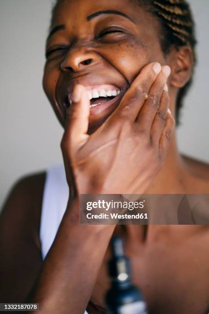 afro woman smiling while touching face - mature woman face beauty stock-fotos und bilder