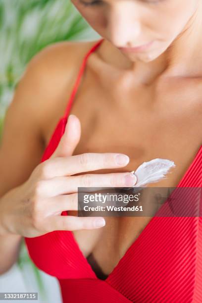 woman applying sunscreen on body - femme décolleté photos et images de collection