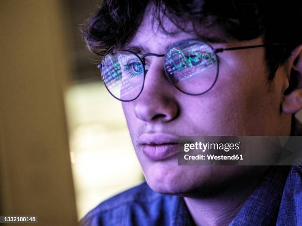 male teenager with stock market data reflection on eyeglasses - teenage boys stock photos et images de collection