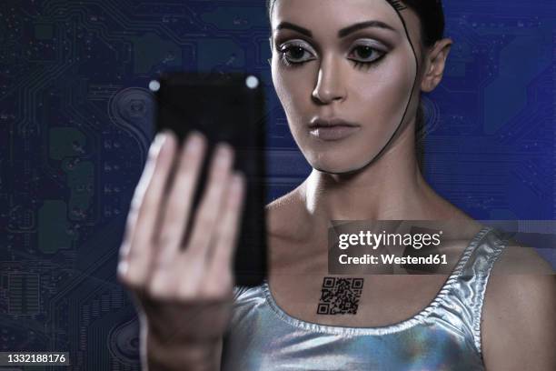 robot woman with barcode on chest looking at smart phone - bionic woman stock pictures, royalty-free photos & images