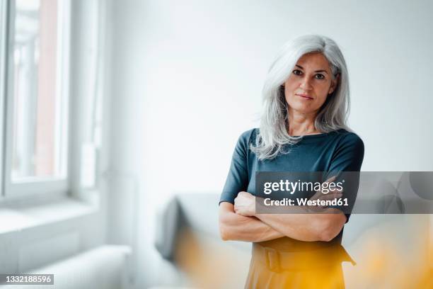 businesswoman with arms crossed standing at office - arms crossed stock pictures, royalty-free photos & images