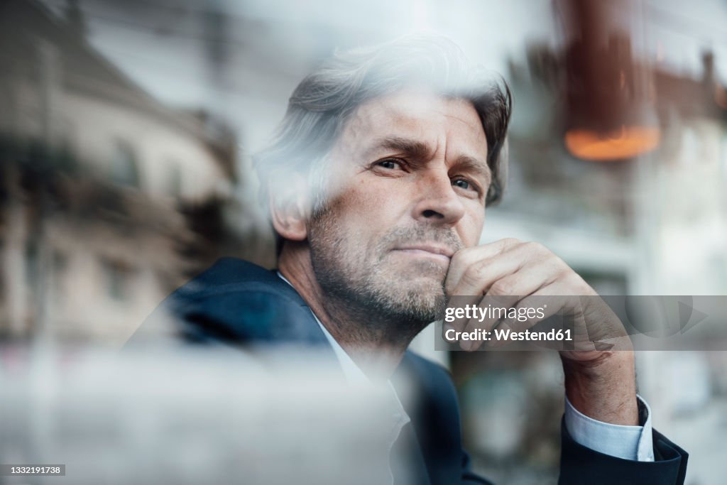 Mature businessman with gray hair and stubble seen through glass window