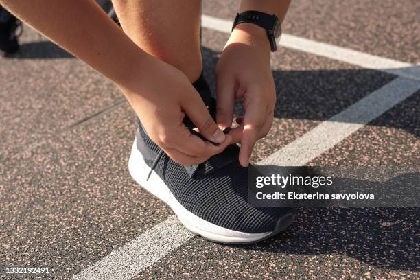 a young boy ties a shoelace on his sneakers on a treadmill. - running legs ストックフォトと画像