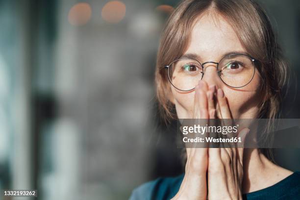 female professional wearing eyeglasses covering mouth with hands - surprise portrait photos et images de collection
