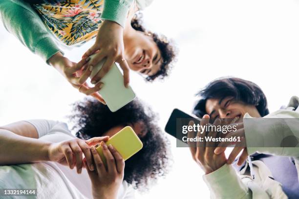 multi-ethnic male and female friends using smart phones - 3 men looking up stock pictures, royalty-free photos & images