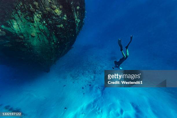 young man swimming towards abandoned ship undersea - competitive diving stock pictures, royalty-free photos & images