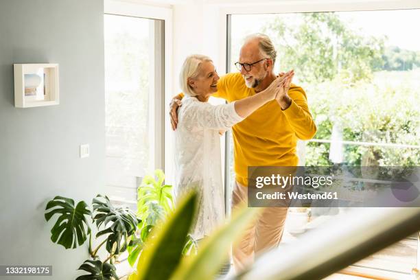 happy mature couple dancing at home - couple dancing at home stockfoto's en -beelden