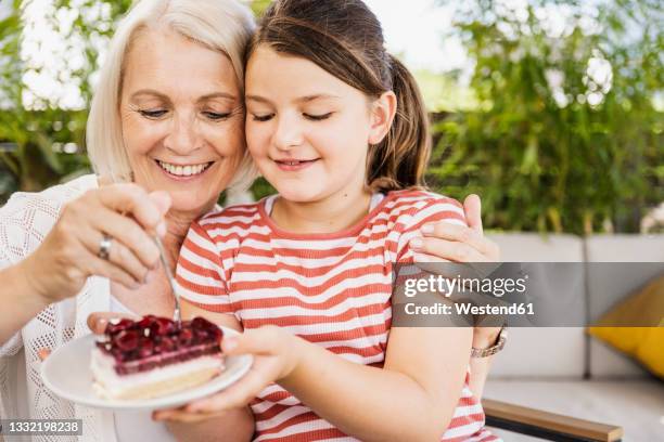 granddaughter and mother eating dessert while sitting at balcony - eating cake stock-fotos und bilder