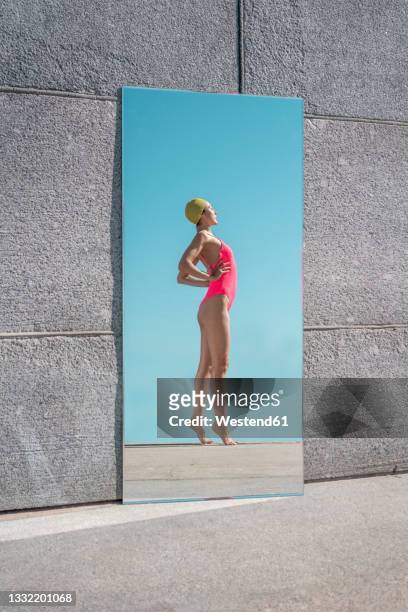 mirror reflection of woman standing with hands on hips during sunny day - full length mirror stock-fotos und bilder