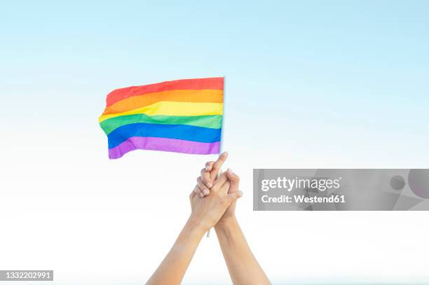 lesbian couple holding rainbow flag - gay flag stockfoto's en -beelden