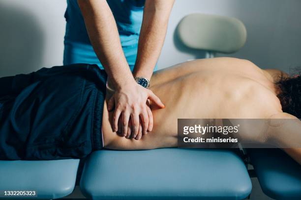 physical therapy: chiropractor doing massage of the patients back - healing hands stockfoto's en -beelden