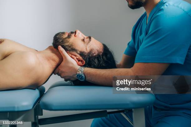 physical therapy:physiotherapist doing neck adjustment while patient is lying on the bed - chiropractic stock pictures, royalty-free photos & images