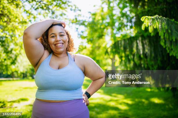 young woman taking a break from  exercising outdoors - fat black man stock-fotos und bilder