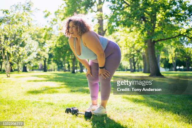 young woman resting while working out with hand weights outdoors - hand on knee stock pictures, royalty-free photos & images