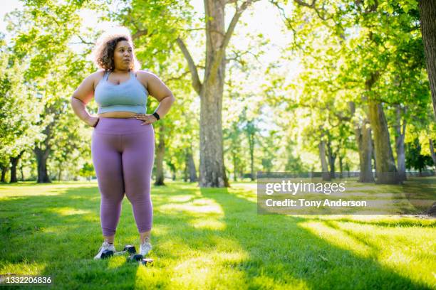 young woman resting while working out with hand weights outdoors - fat black man stock-fotos und bilder